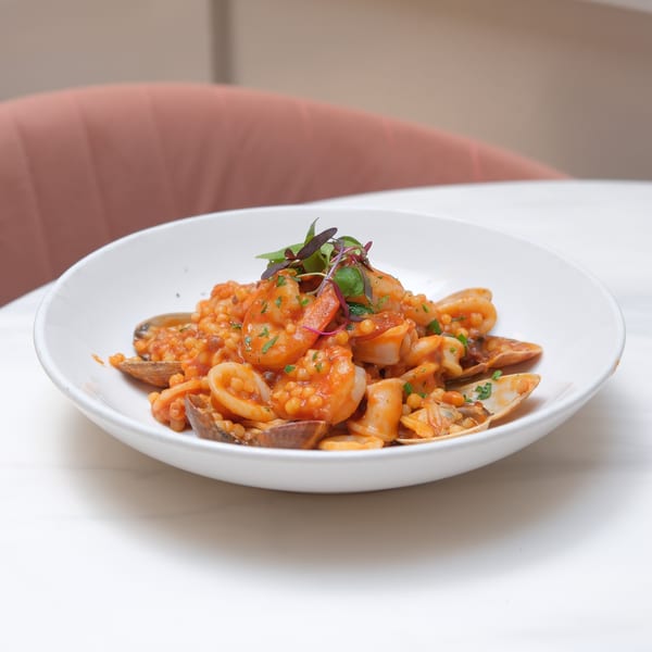 Doppio Zero's Italian seafood pasta with shrimp, clams, and squid in a white bowl.