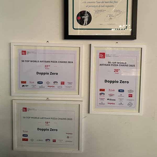 Three framed awards for Doppio Zero, recognizing it as a top artisan pizza chain from 2023-2025.