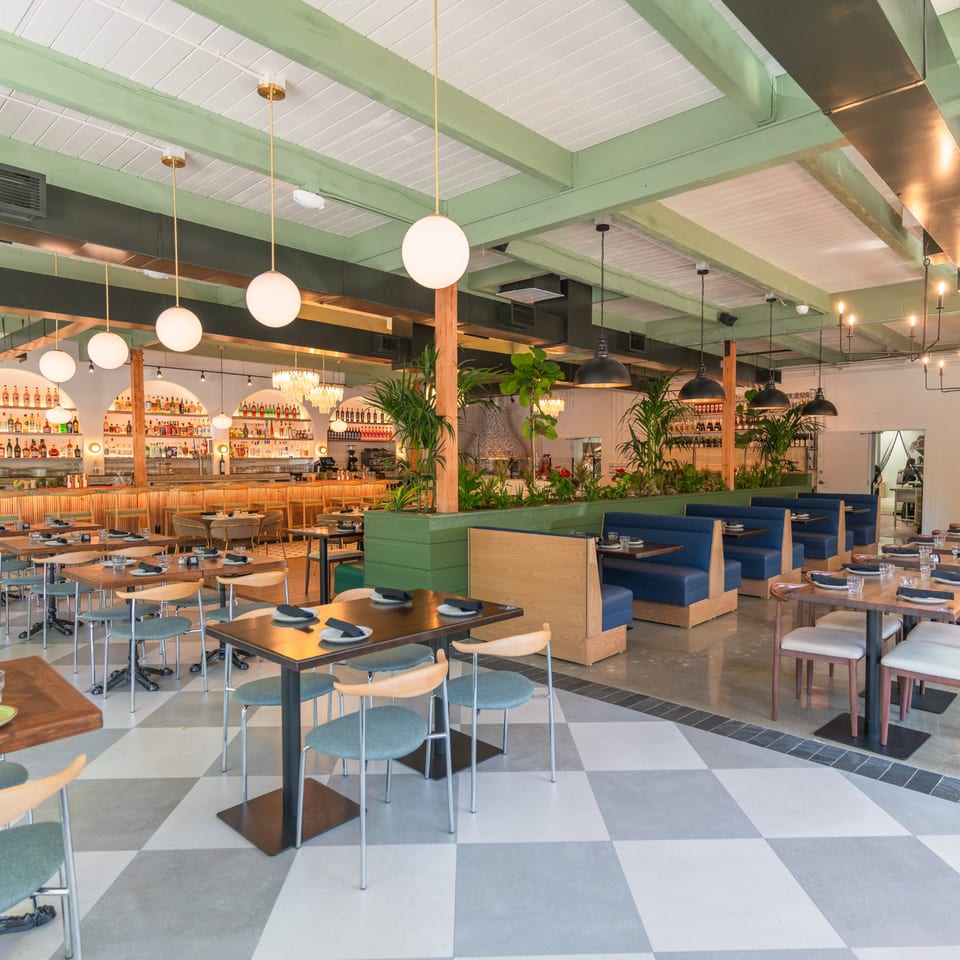 Spacious Doppio Zero dining room with checkered floors, blue booths, and a long bar with liquor bottles.