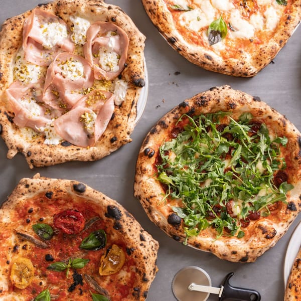 Four different Italian pizzas with various toppings, including mortadella, arugula, and anchovies.