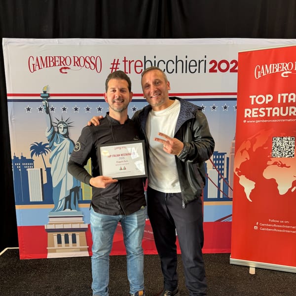 Two men smiling, one holding a "Top Italian Restaurants 2026" award for Doppio Zero.