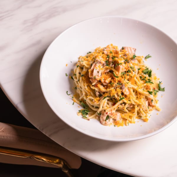 Doppio Zero's spaghetti with shrimp, mushrooms, and orange breadcrumbs, garnished with parsley.