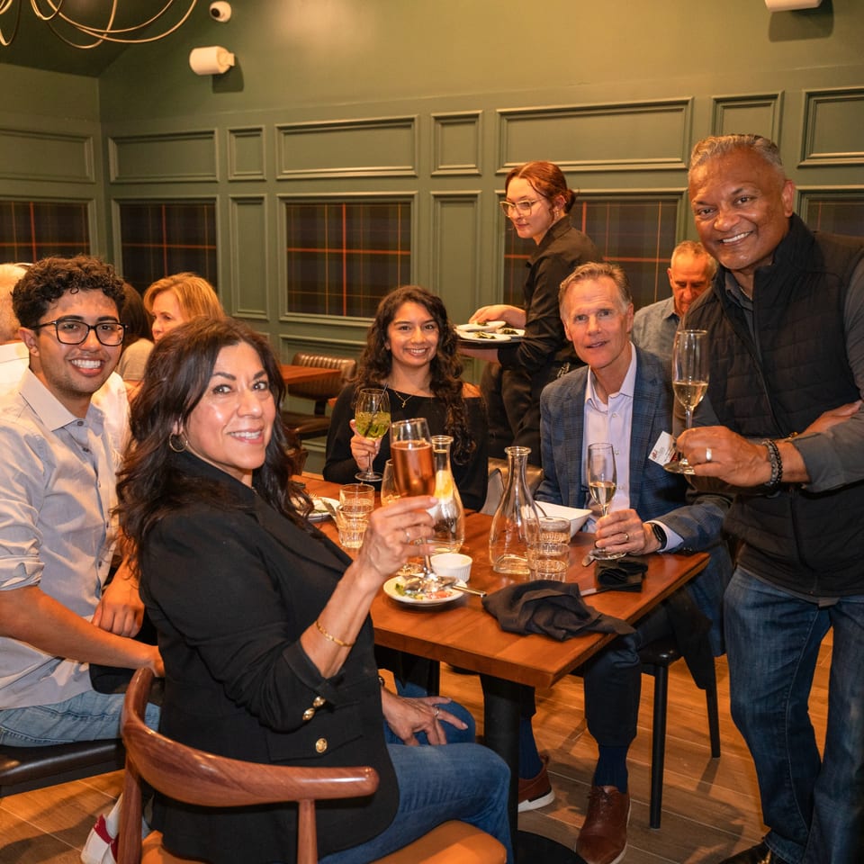 Diverse group of friends toasting with champagne and wine at a restaurant table.