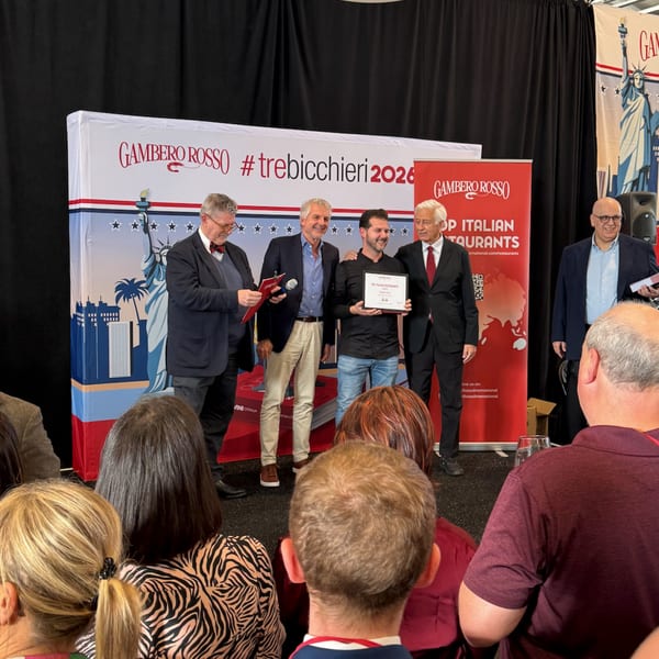 Four men on stage, one holding an award, in front of a Gambero Rosso banner.